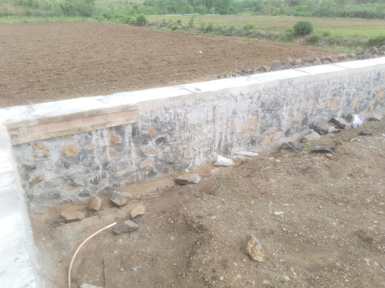 Coursed rubble stone compound wall with cement coping