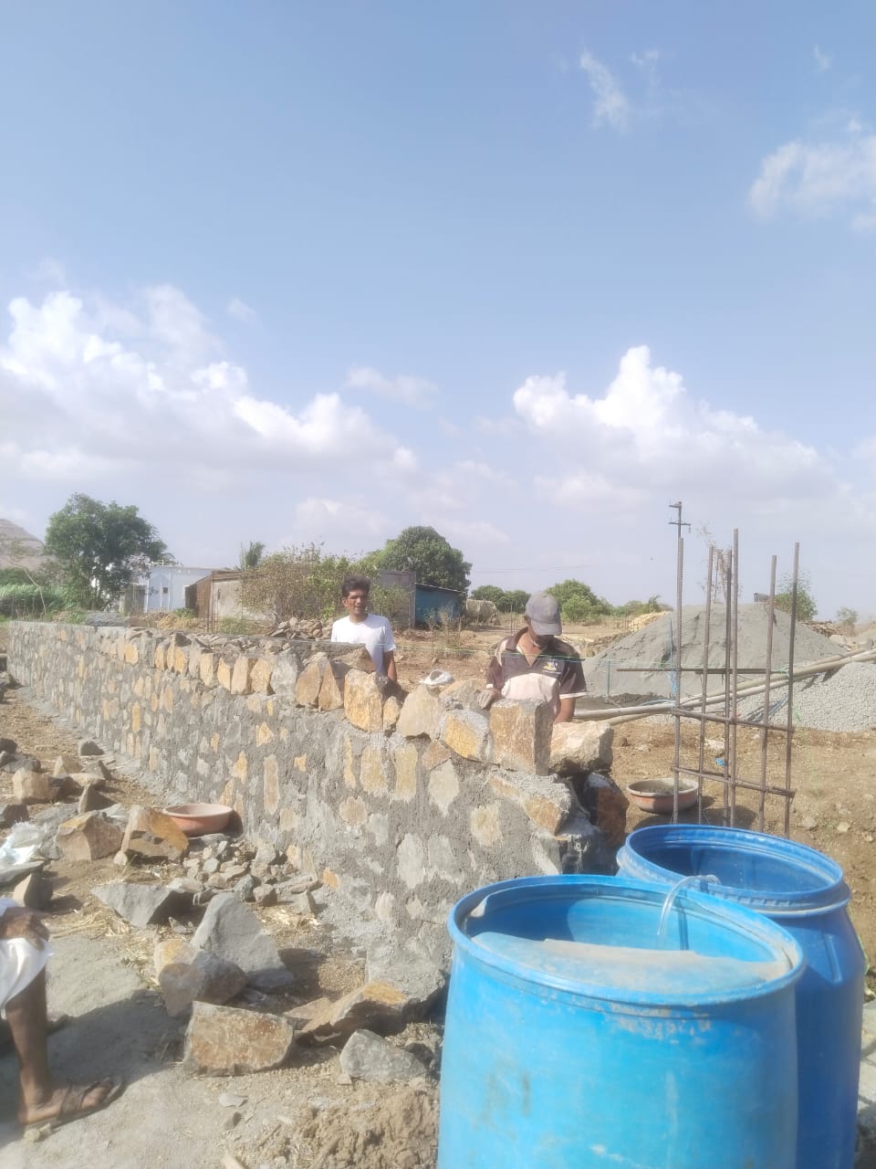 Skilled masons building a natural stone wall on a site in Maharashtra