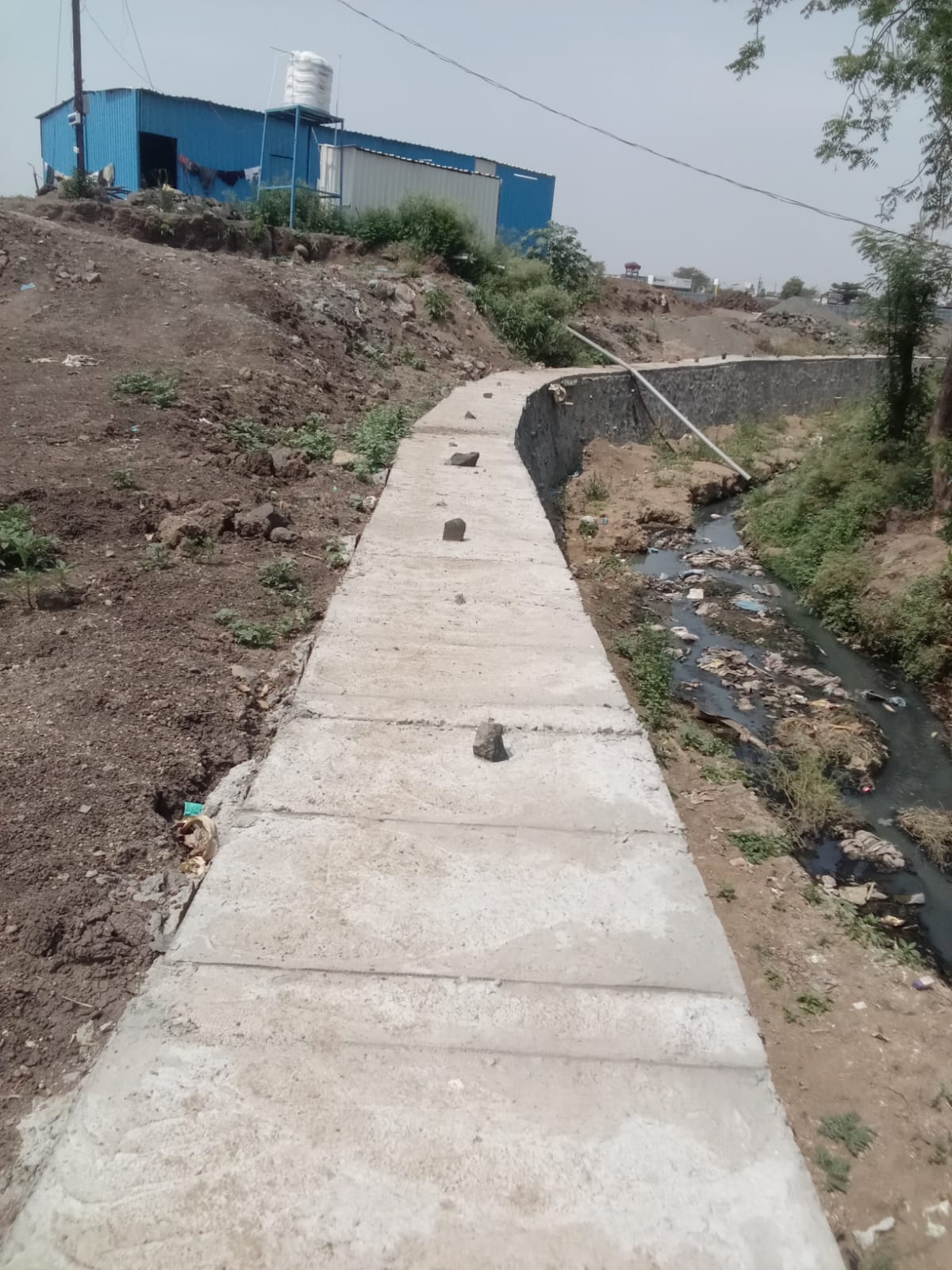 Concrete nala lining pathway beside a stone wall