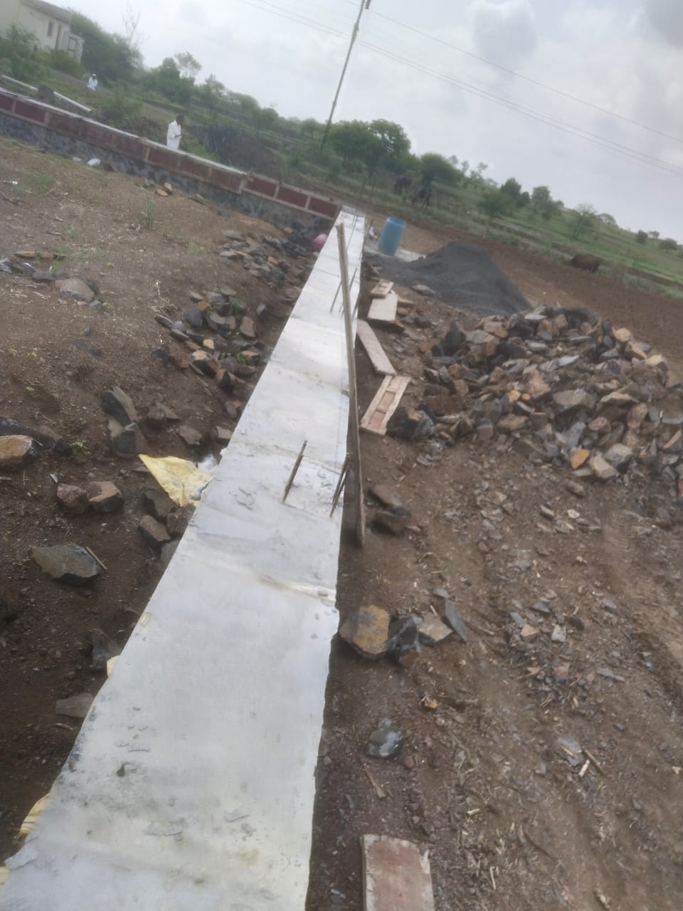 Stone retaining wall with concrete coping along a farm plot